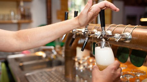 Eine Servicekraft zapft frisches Bier in ein Glas. Restaurant und Gastronomie leiden unter Personalmangel nach der Corona Pandemie. (Foto: picture-alliance / Reportdienste, Picture Alliance)