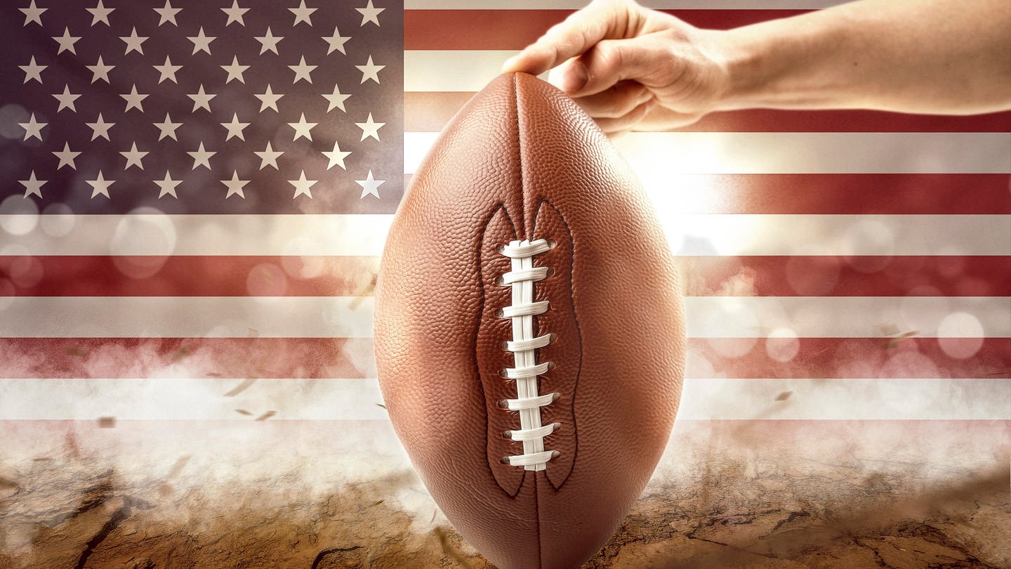 Superbowl bei SWR1!  Der Super Bowl ist das Finale der US-amerikanischen American Football Profiliga National Football League NFL. Das Symbolbild zeigt einen Football vor der amerikanischen Flagge (Foto: picture-alliance / Reportdienste, picture alliance / CHROMORANGE | Michael Bihlmayer)
