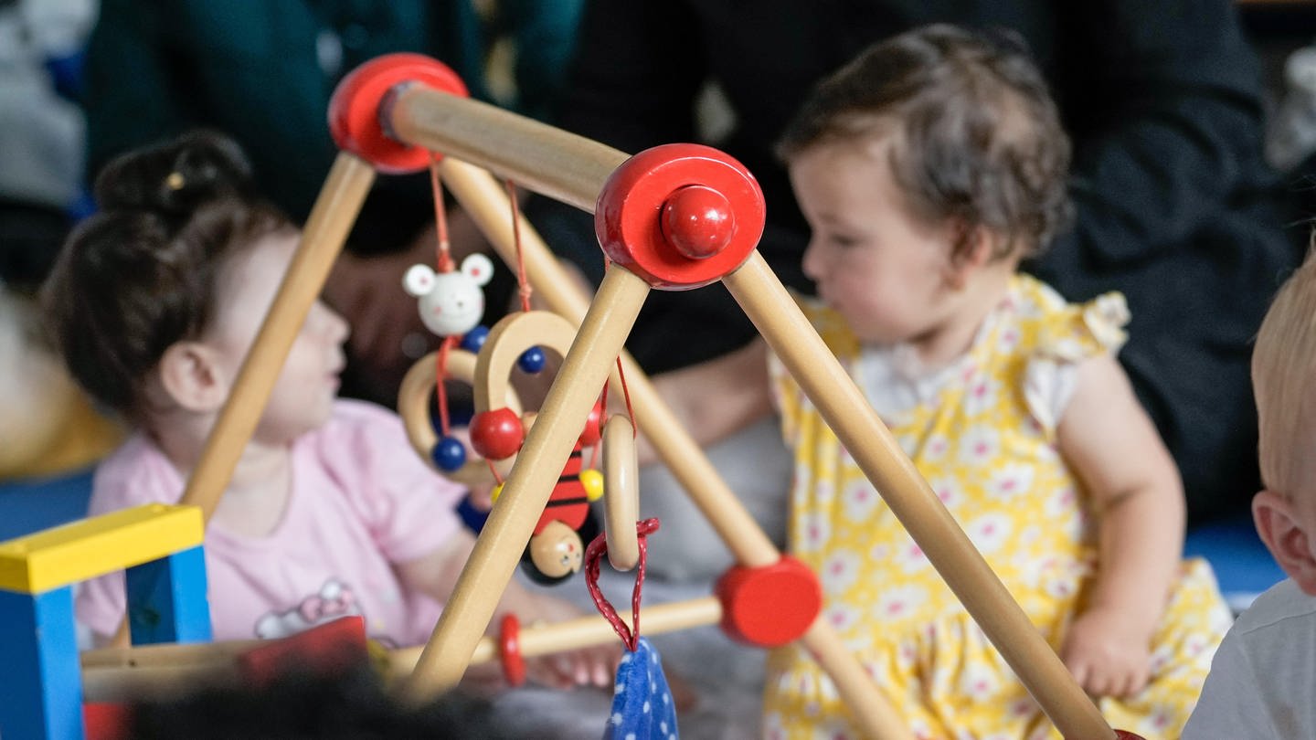 Kinder spielen auf dem Boden mit einem Holzspielzeug. Katharina Pommer ist Familientherapeutin und Autorin. In ihrem Buch 