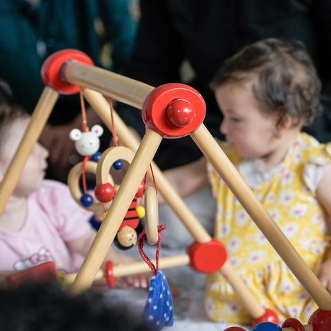 Kinder spielen auf dem Boden mit einem Holzspielzeug. Katharina Pommer ist Familientherapeutin und Autorin. In ihrem Buch "Das Kind in mir kann mich mal" zeigt sie, welches Potenzial in uns steckt. (Foto: picture-alliance / Reportdienste, Picture Alliance)