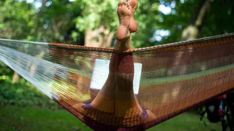 Mensch in bunter Netzhängematte der die Füße raushängen lässt (Foto: dpa Bildfunk, Picture Alliance)