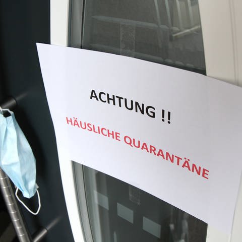 Ein Schild mit der Aufschrift "Häusliche Quarantäne" an der Eingangstür zu einem Wohnhaus (Foto: IMAGO, Fleig/Eibner-Pressefoto)