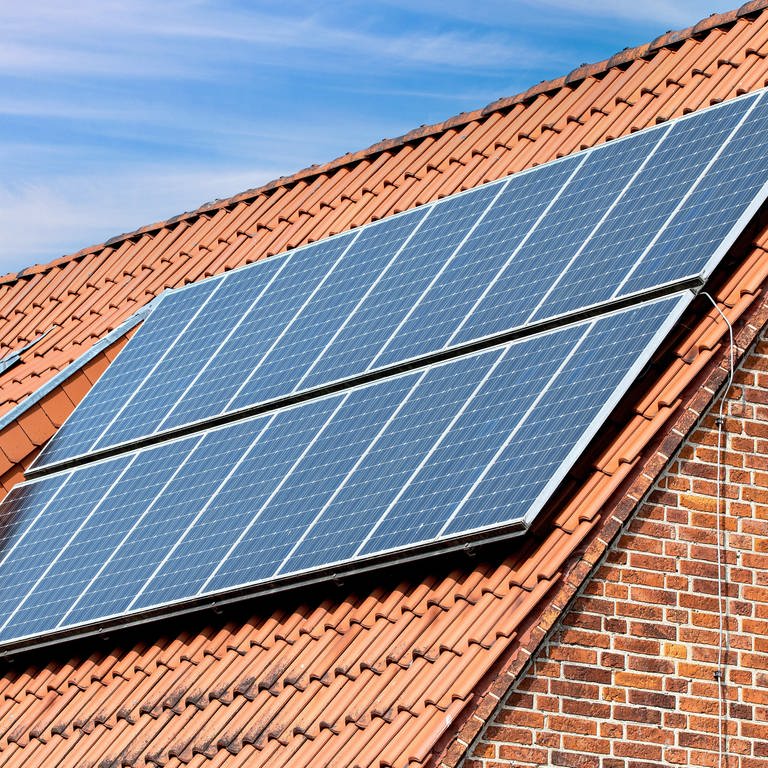 Eine Solaranlage auf dem Dach eines älteren Privathauses mit roten Klinkersteinen sorgt für sauberen, umweltfreundlichen Strom.