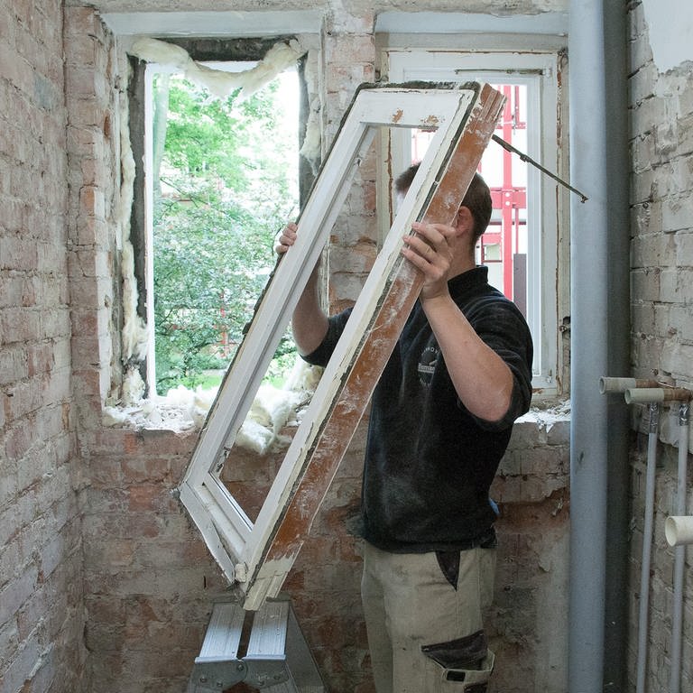Ein Handwerker tauscht bei einer Sanierung ein altes Fenster aus - Wußten Sie: Ein Viertel der Wärme geht in einem normalen Einfamilienhaus über die Fenster verloren! So sanieren Sie richtig.