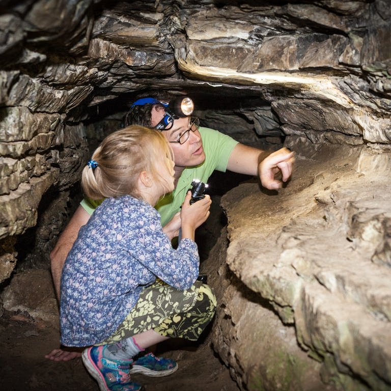 Ein Mann und eine Frau kauern mit Stirnlampen in der Sieben-Täler-Höhle. Die Sieben Täler Runde bei Rottenburg gehört zu den schönsten Wanderwegen in Baden-Württemberg. (Foto: Hammer)