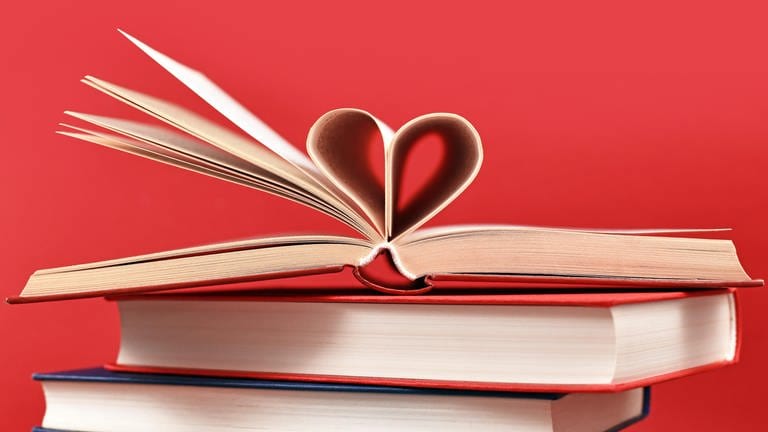 Buchtipps: Bücher liegen aufeinander gestapelt, ein paar Seiten bilden ein Herz