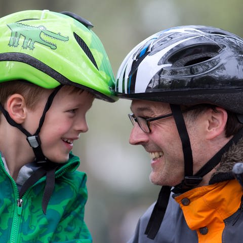 Ein Junge und ein Mann tragen Fahradhelme und lachen sich gegenseitig an (Foto: picture-alliance / Reportdienste, picture alliance / dpa | Friso Gentsch)