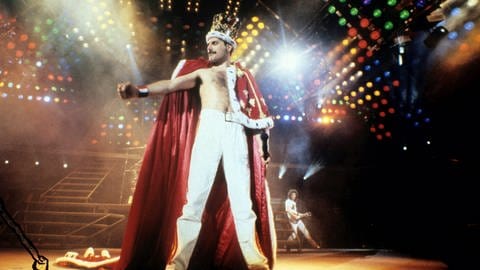 Freddie Mercury von der Band Queen auf der Bühne mit einer Krone und Umhang an (Foto: picture-alliance / Reportdienste, Photoshot)