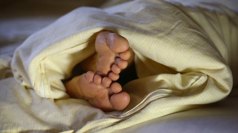 Die Füße einer Frau ragen unter einer Bettdecke hervor (Foto: dpa Bildfunk, picture alliance/Karl-Josef Hildenbrand/dpa)