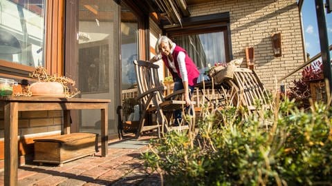 Eine Frau klappt ihre Gartenmöbel ein und stellt sie über den Herbst und Winter zurück ins Haus (Foto: picture-alliance / Reportdienste, Christin Klose)