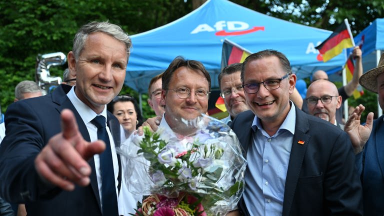 Björn Höcke (l.) , Vorsitzender der AfD Thüringen und Tino Chrupalla, AfD-Bundesvorsitzender (r.) gratulieren dem Wahlsieger des Thüringer Kreis Sonneberg, Robert Sesselmann (AfD, M) im Garten eines Restaurants. 