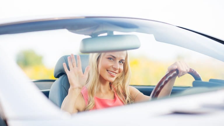 Freundliche Autofahrerin bedankt sich mit einem Handgruß
