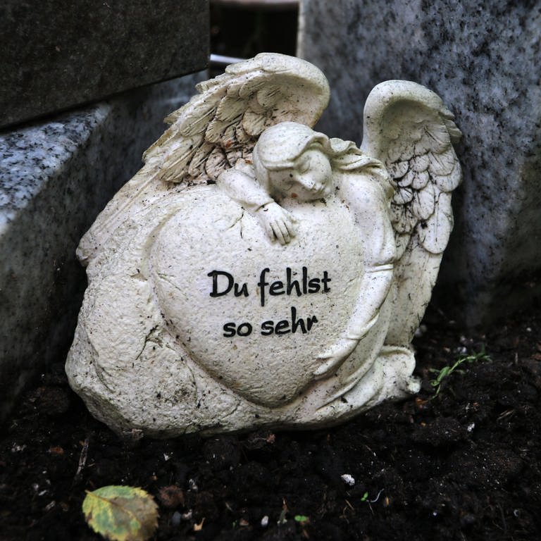 Auf einem Grab eines Sternenkindes steht eine Engel-Figur, die ein Herz mit der Aufschrift "Du fehlst so sehr" trägt (Foto: picture-alliance / Reportdienste, Ina Fassbender)
