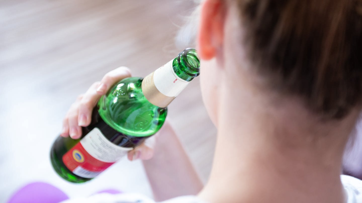 Alkoholsucht bei Jugendlichen: Ein Mädchen wurde von hinten fotografiert, wie sie aus einer Bierflasche trinkt (Foto: picture-alliance / Reportdienste, picture alliance/dpa | Silas Stein)
