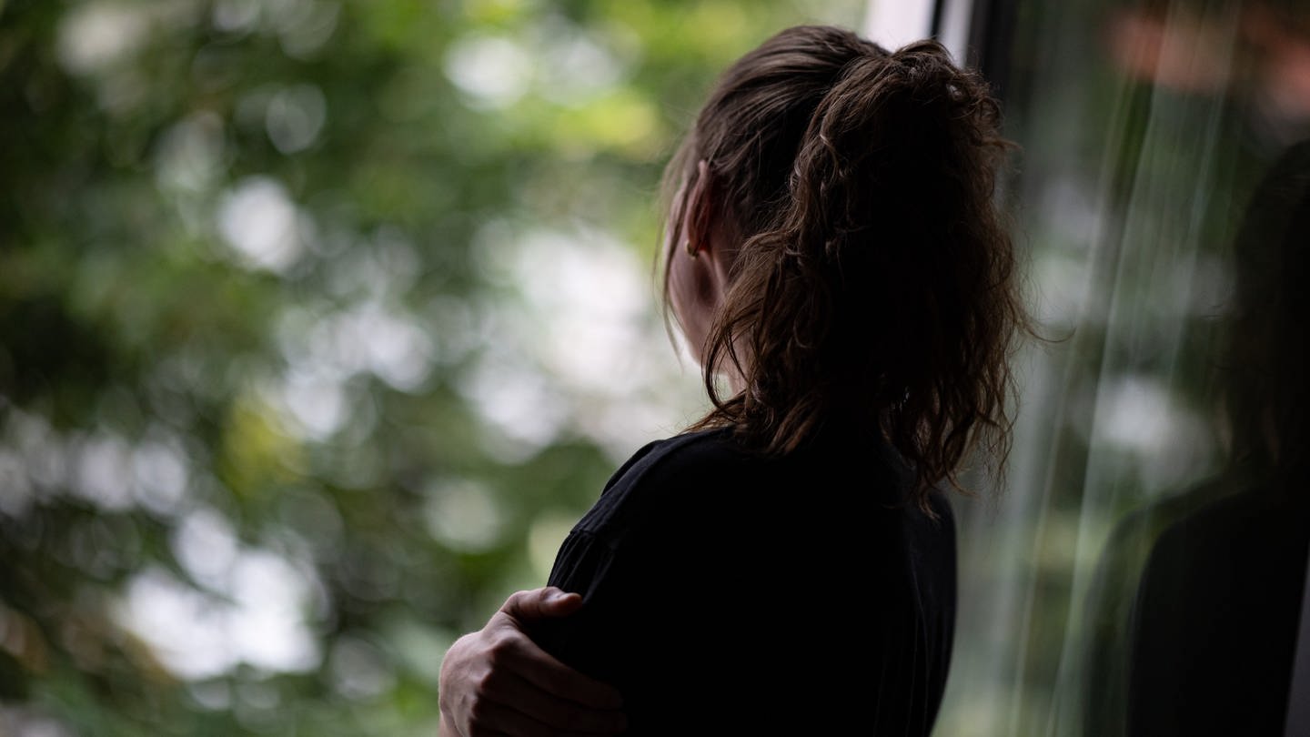 Eine Frau steht in einer Wohnung und schaut durch ein Fenster nach draußen. (Foto: picture-alliance / Reportdienste, dpa Bildfunk, picture alliance/dpa | Fabian Sommer)