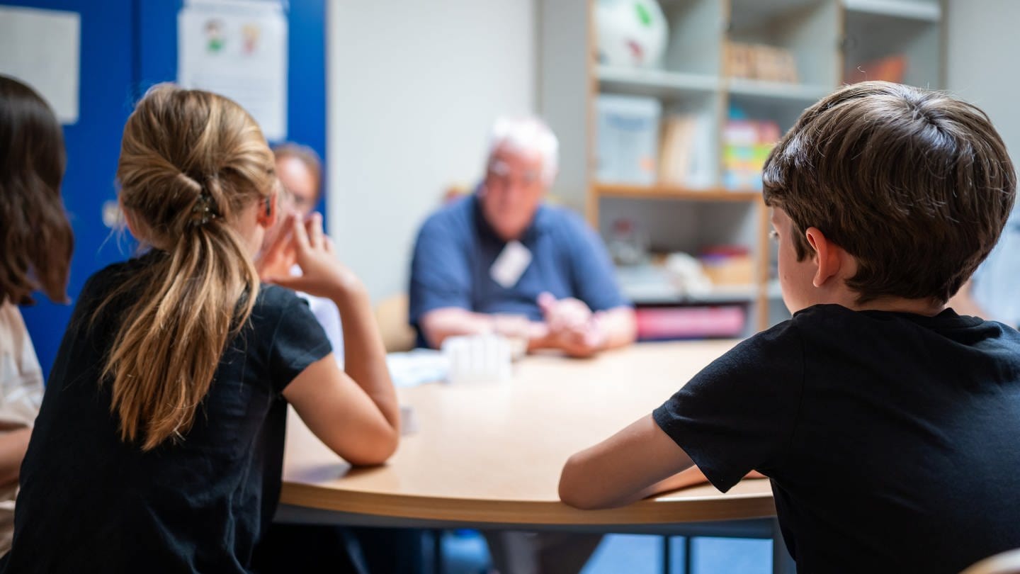 Grundschüler sitzen an einem Tisch und sprechen mit Mediatoren (Foto: dpa Bildfunk, picture alliance/dpa | Philipp Schulze)