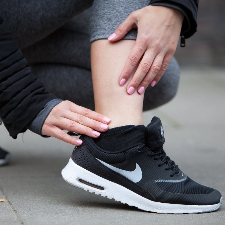Sportverletzung beim Laufen: Eine Frau fasst sich an ihren schmerzenden Knöchel (Foto: picture-alliance / Reportdienste, picture alliance / dpa Themendienst | Christin Klose)