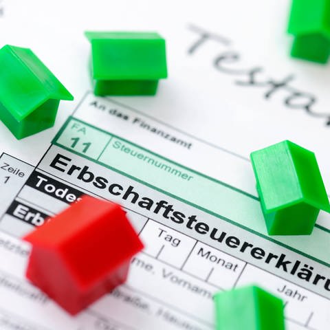 Kleine Hausmodelle in grün und rot liegen auf einer Erbschaftsteuererklärung (Foto: picture-alliance / Reportdienste, picture alliance | Christian Ohde)
