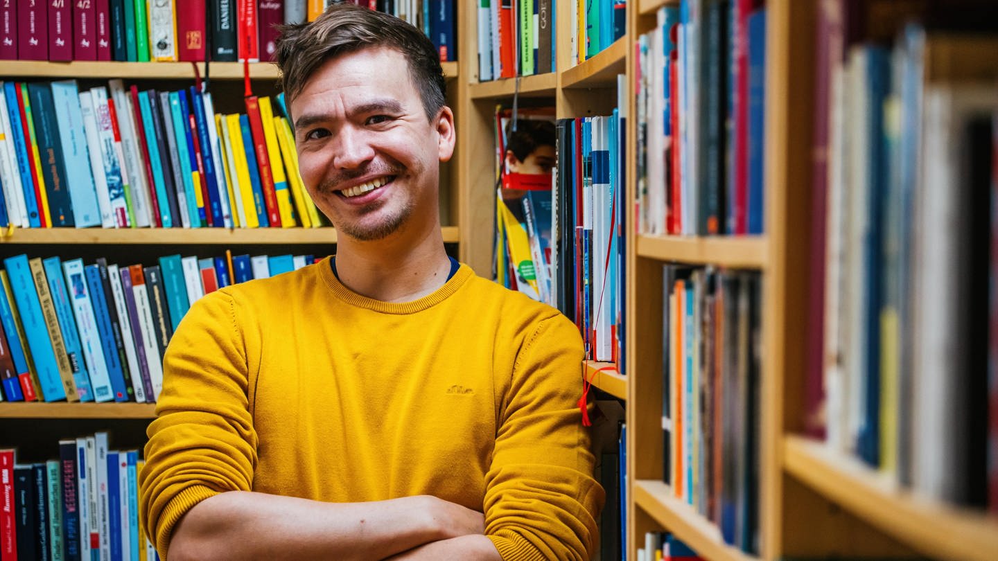 Gymnasiallehrer und Bildungsinfluencer Bob Blume steht lächelnd vor Bücherregalen (Foto: dpa Bildfunk, picture alliance/dpa | Philipp von Ditfurth)