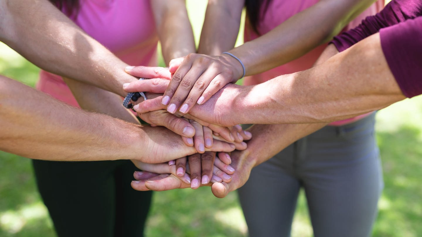 Eine Gruppe Personen trägt pinke Oberteile und stapelt ihre Hände (Foto: picture-alliance / Reportdienste, picture alliance / Zoonar | Channel Partners)