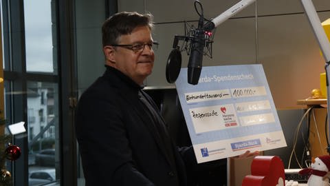 Andreas Manthe, Vorstand der Sparda-Bank Südwest Stiftung im SWR1 Studio mit einem Scheck über 100 000 € für Herzenssache. (Foto: SWR)