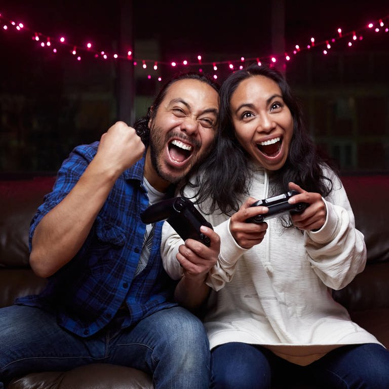 Ein Mann und eine Frau sitzen auf einer Couch und spielen Videospiele. (Foto: dpa Bildfunk, picture alliance / Shotshop | Addictive Stock)