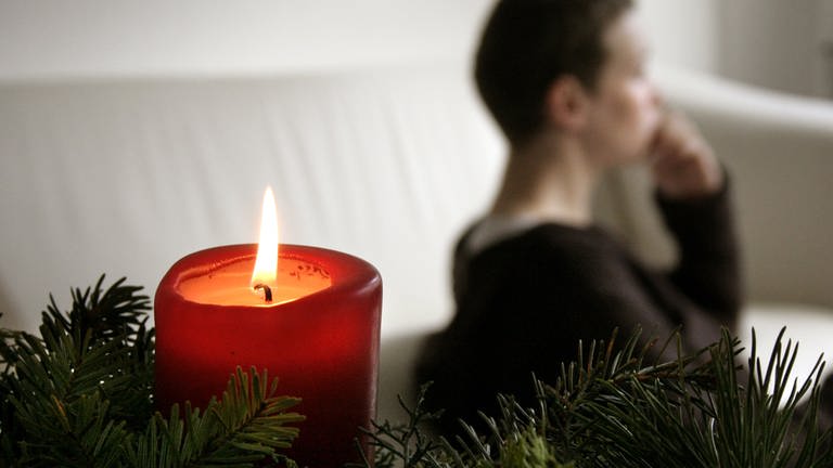 Trauer und Einsamkeit an Weihnachten: Eine nachdenkliche Frau bei Kerzenlicht. (Foto: dpa Bildfunk, picture alliance / Caro | Scheffbuch)