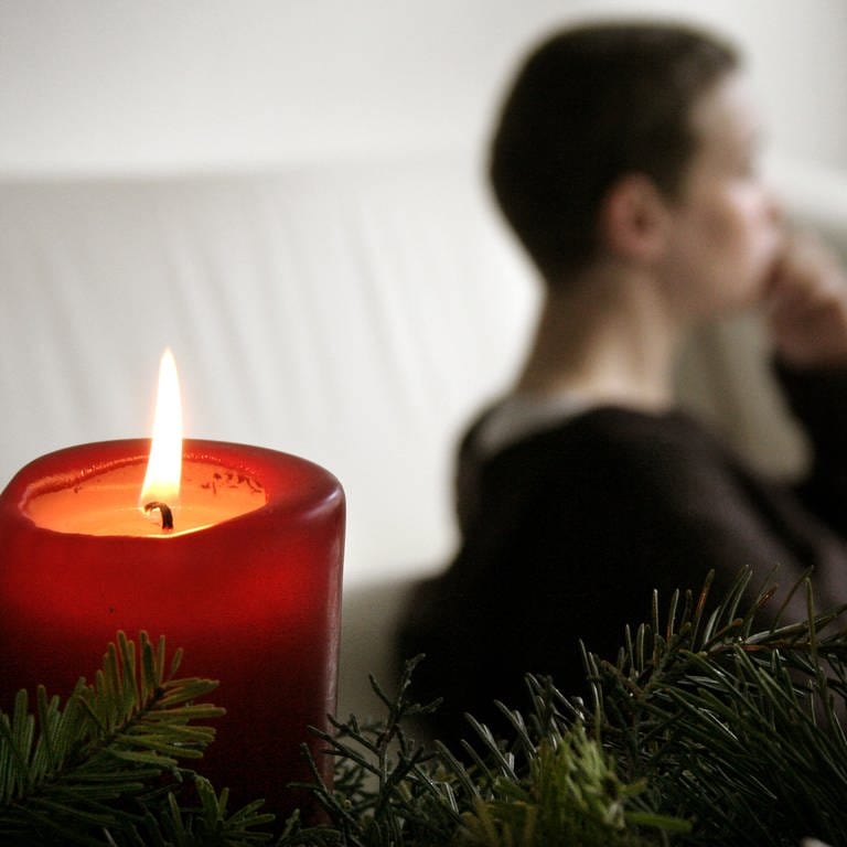 Trauer und Einsamkeit an Weihnachten: Eine nachdenkliche Frau bei Kerzenlicht. (Foto: dpa Bildfunk, picture alliance / Caro | Scheffbuch)
