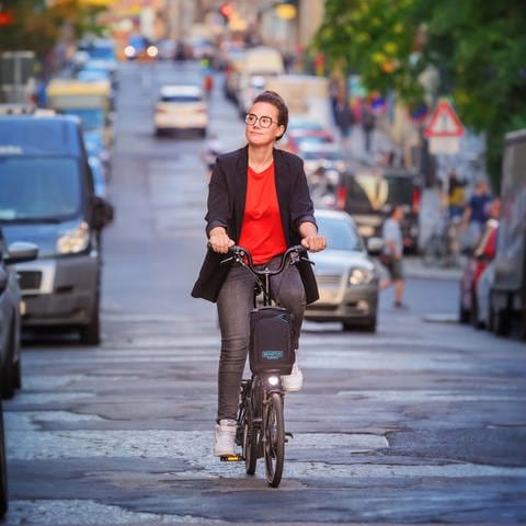Mobilitätsexpertin Katja Diehl spricht in SWR1 Leute über den fairen und gerechten Weg zur Verkehrswende. Im Bild fährt Katja Diehl auf einem Fahrrad auf einer gepflasterten Straße.