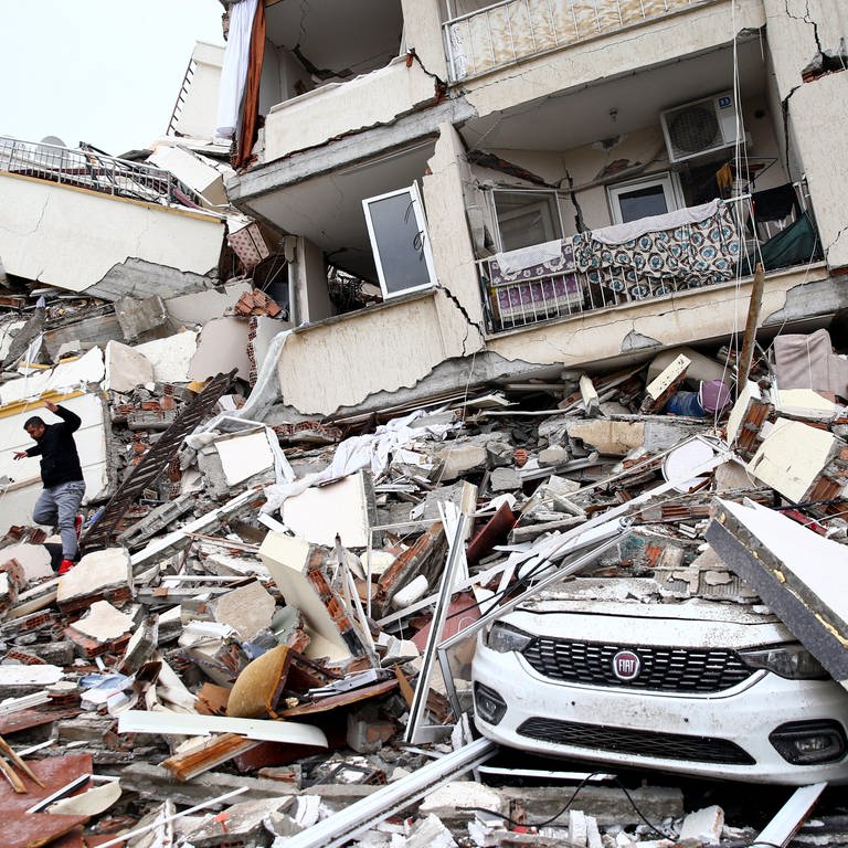Erdbeben in der Türkei und Syrien: ein Mann auf dem Schuttberg eines zerstörten Hauses. In SWR1 Leute erzählt Pamela Orgeldinger von Care Deutschland, wie wichtig - und wie schwierig - schnelle Hilfe für die Erdbebenopfer jetzt ist.