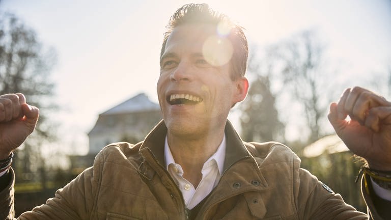 Wissenschaftsjournalist Bas Kast lacht, im Hintergrund scheint die Sonne. In SWR1 Leute spricht der Erfolgsautor von "Ernährungskompass" darüber, wie man sein inneres Gleichgewicht finden kann. Das verrät er in seinem Buch "Kompass für die Seele". (Foto: Mike Meyer)