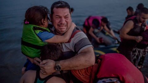 Laith Majid al Amiri cries as he holds his youngest children as they arrived on the Greek island of Kos.  (Foto: Daniel Etter photography)