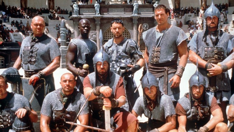 Ralf Moeller (hinten, 2.v.r.) gehört zu den Gladiatoren, die in der Arena von Rom um ihr Leben kämpfen im Hollywood-Film "Gladiator" aus dem Jahr 2000. (Foto: picture-alliance / Reportdienste, picture-alliance / dpa | UIP)