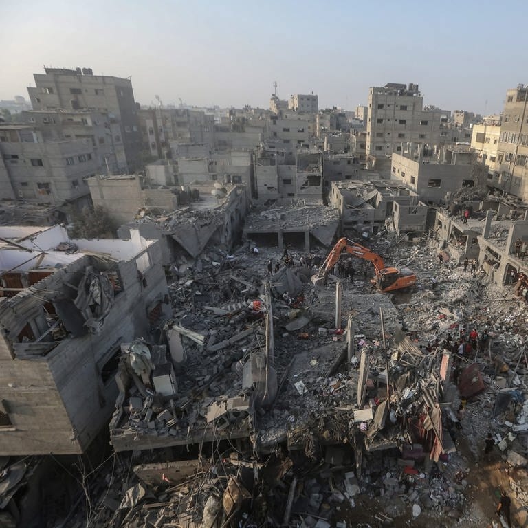 Ein Bagger räumt Trümmer weg, während Menschen nach israelischen Luftangriffen in Gebäuden nach Überlebenden suchen. (Foto: dpa Bildfunk, picture alliance/dpa | Mohammed Talatene)