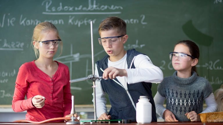 Kinder mit Schutzbrille experimentieren im Unterricht.
