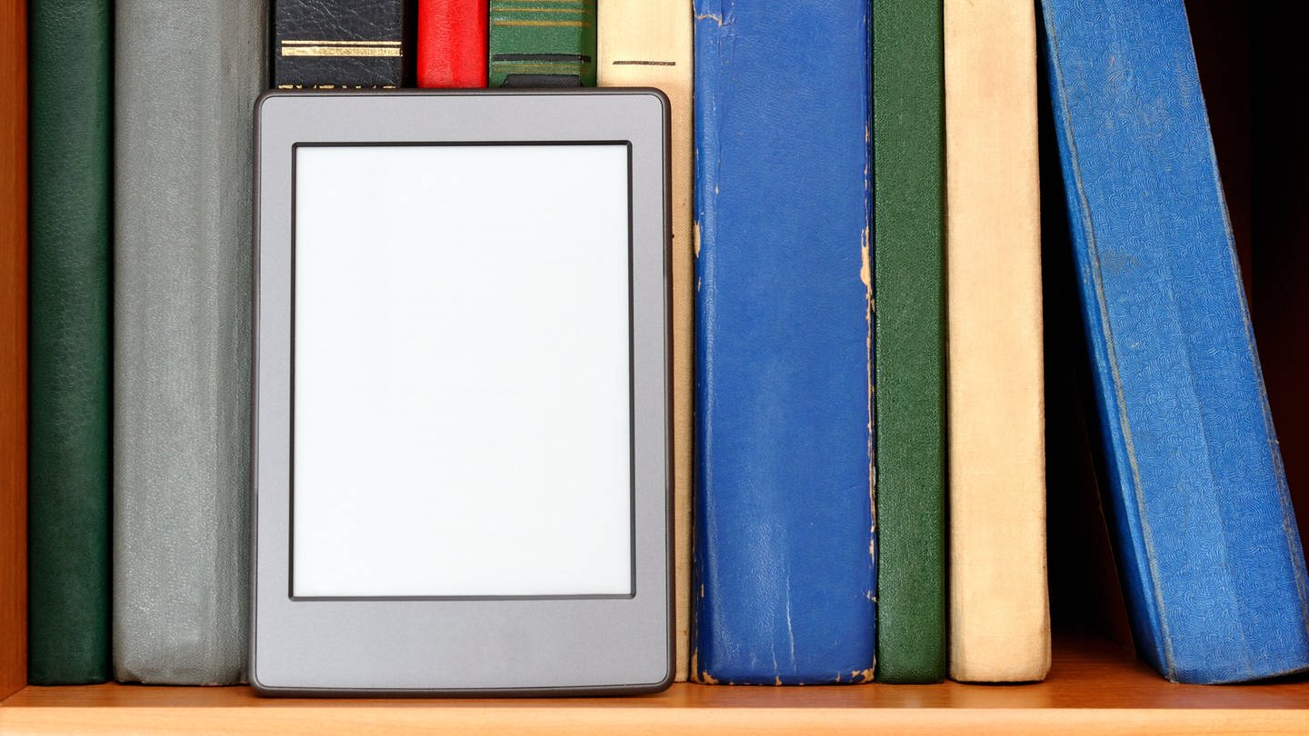 Ebook-Reader vor einer bunten Bücherwand (Foto: IMAGO, IMAGO / agefotostock)
