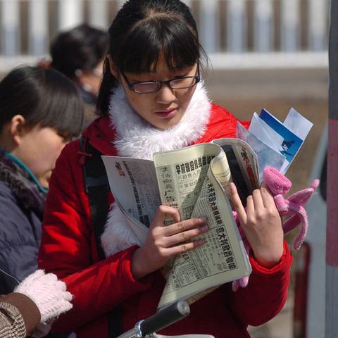 Junge Chinesinnen studieren die Jobangebote in Zeitungen (Foto: IMAGO, IMAGO / Xinhua)