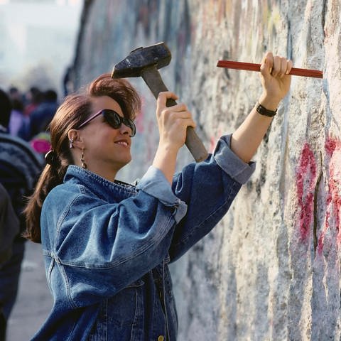 Fall der Berliner Mauer: Eine Frau schlägt Stücke aus der Mauer  (Foto: picture-alliance / Reportdienste, picture alliance / imageBROKER | KFS)