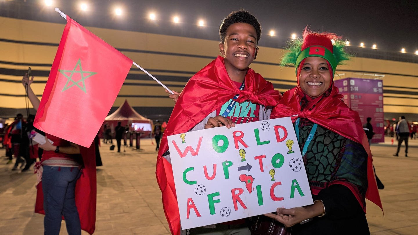 Zwei marokkanische Fans, ein junger Mann und eine Frau, halten ein Schild auf dem steht 