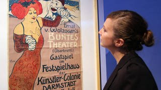 Eine Besucherin betrachtet die Plakatkunst der Künstlerkolonie Darmstadt das Plakat Ernst von Wolzogen s Buntes Theater von Edmund Edel aus dem Jahr 1901. (Foto: imago images, IMAGO / epd)