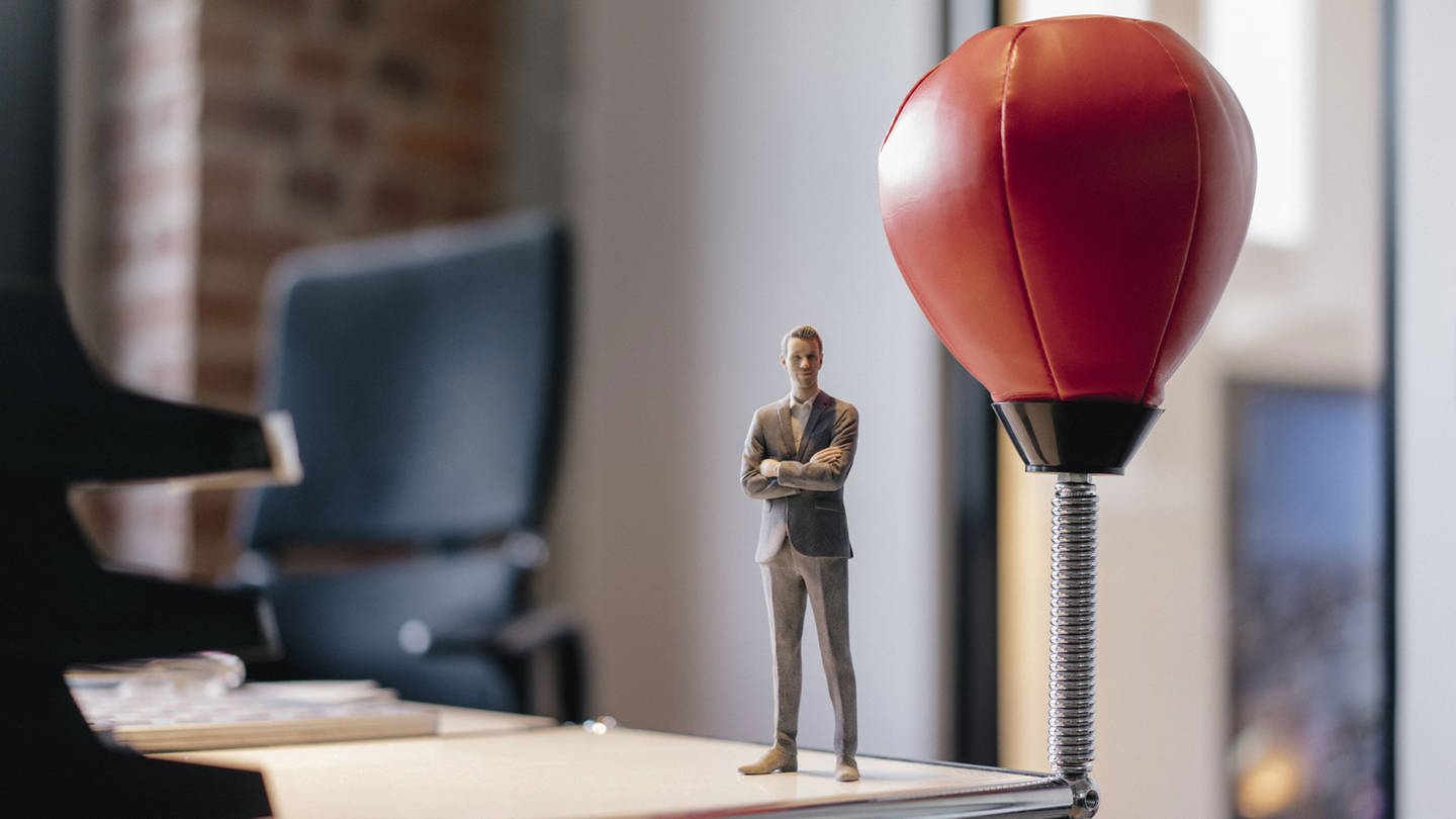Businessman figurine standing on desk by punching ball model released Symbolfoto (Foto: IMAGO, Westend61)