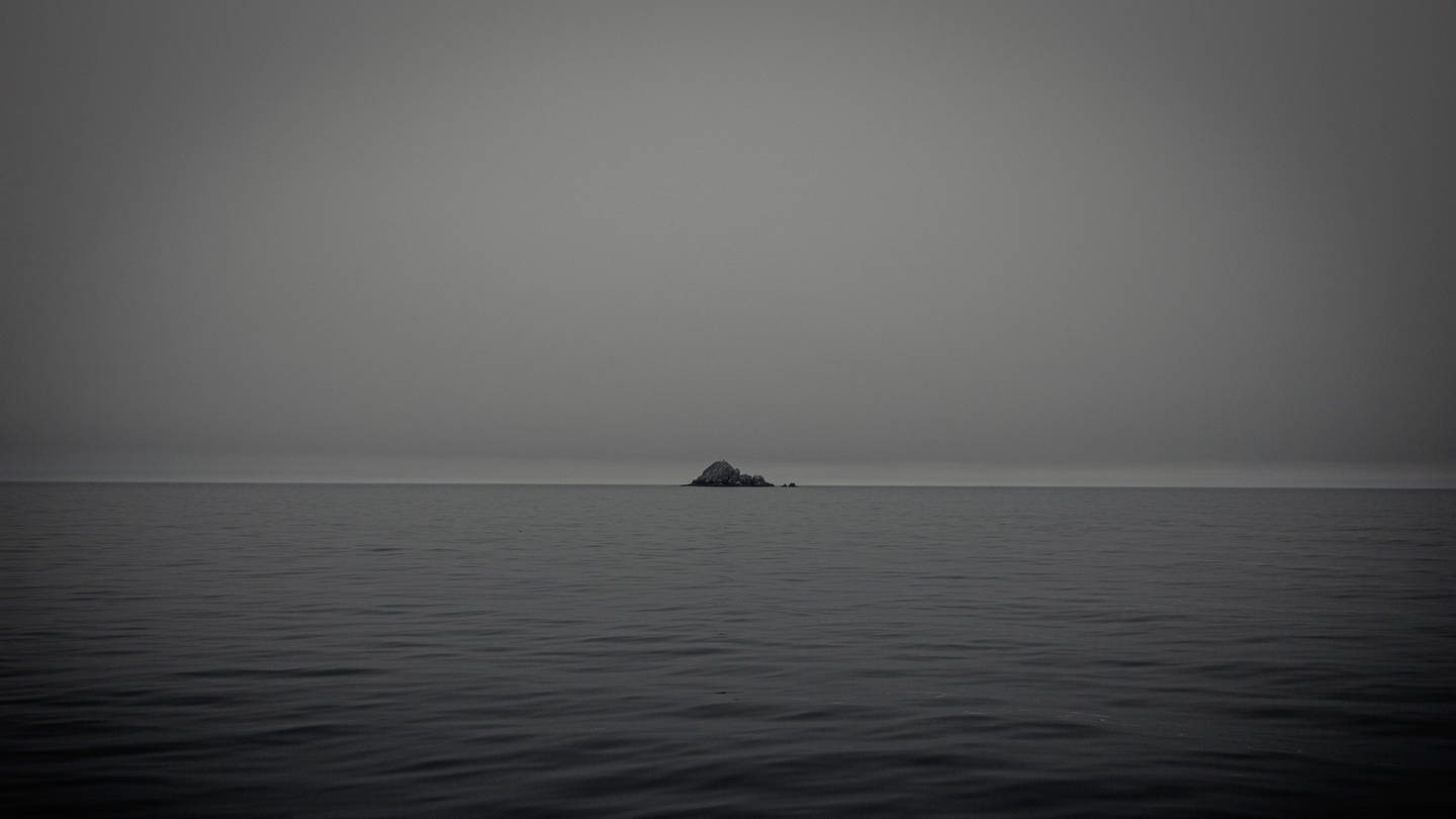 Wasser und in der Ferne eine Insel (Foto: Unsplash / Denys Nevzhai)