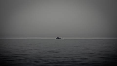 Wasser und in der Ferne eine Insel (Foto: Unsplash / Denys Nevzhai )
