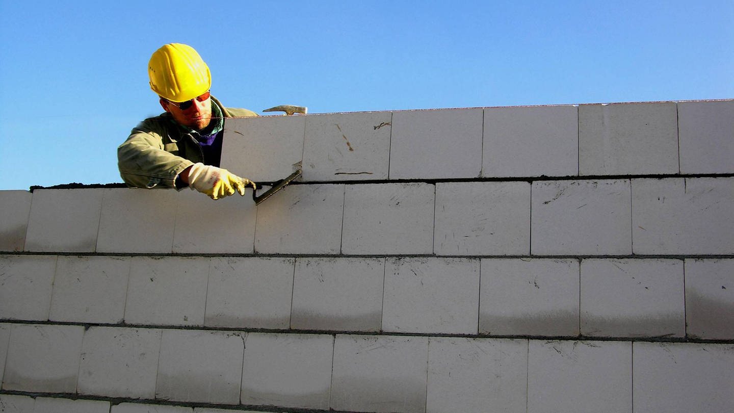 Mann beim Bauen einer Mauer (Foto: IMAGO, imago images / INSADCO)