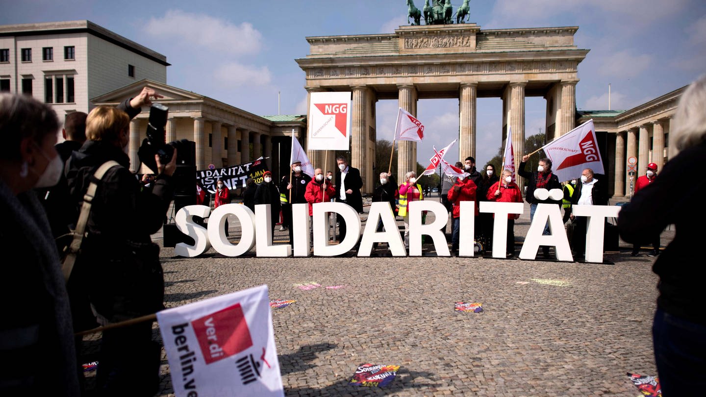 Demonstranten von verdi und NGG mit Banner Solidarität vor dem Brandeburger Tor in Berlin
