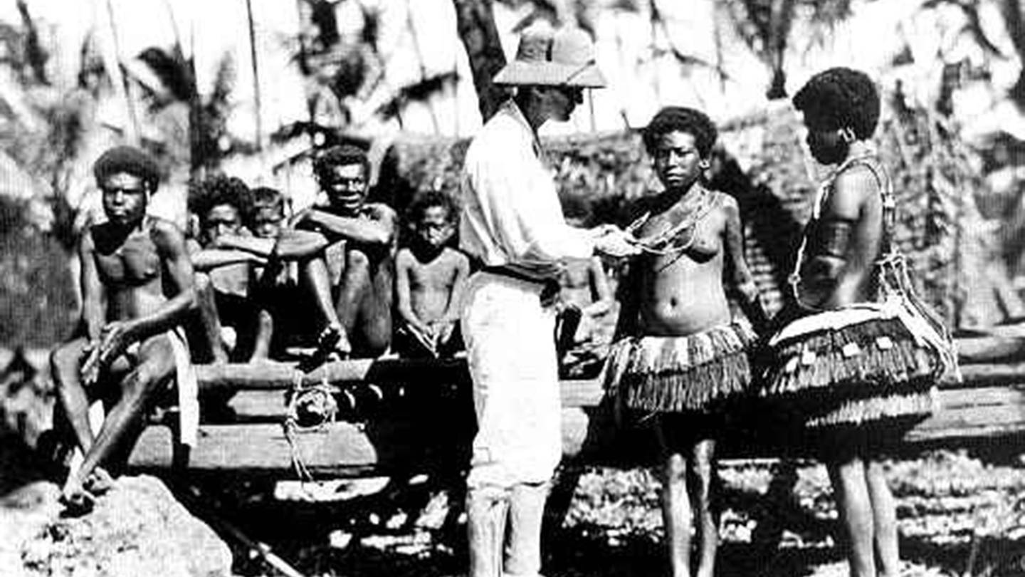 Mann in weißer Uniform mit Eingeborenen (Foto: gemeinfrei / von 1918)