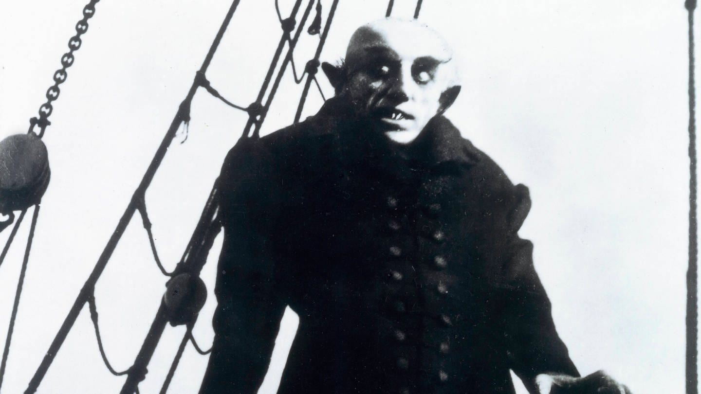 Der Stummfilm-Vampir Nosferatu steht auf einem Schiff und sieht gruselig aus.