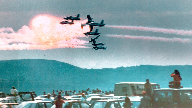 Flugzeuge eines italienischen Kunstflugteams kollidieren über dem US-Luftwaffenstützpunkt Ramstein, bevor sie in die Menge stürzen und 70 Menschen töten. (Foto: ard-foto s2-intern/extern, SWR/picture alliance/AP Photo/Charles Daughty)