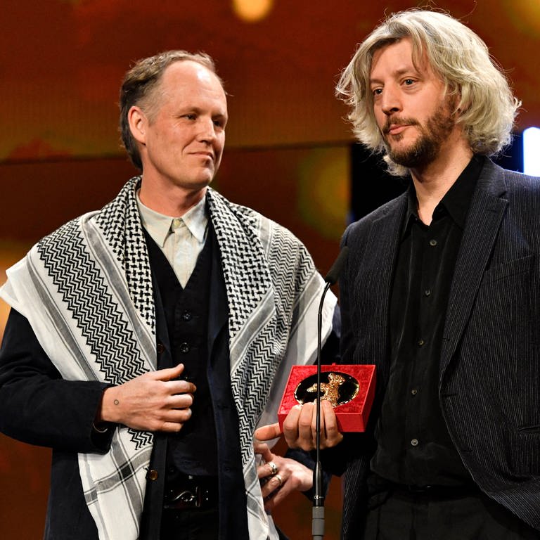 Der amerikanische Filmemacher Ben Russell trägt ein Palästinensertuch als er mit Guillaume Cailleau den Preis der Jury von Encounters bei der Berlinale 2024 entgegen nimmt (Foto: IMAGO, Imago)