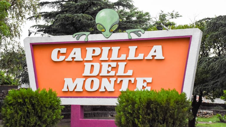 Ortsschild von Capilla del Monte. Auf dem Ortsschild sitzt die Figur eines Außerirdischen. (Foto: SWR, Walter Filz)